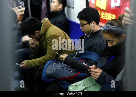 --FILE--Chinese passagers utilisent leurs smartphones pour surfer sur Internet sur une rame de métro à Beijing, Chine, 14 décembre 2015. Pour la première fois, mor Banque D'Images