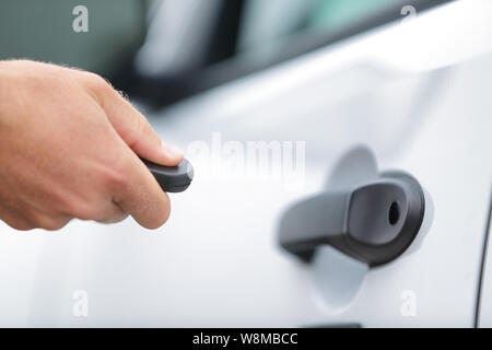 Location de télécommande porte-clé. Chauffeur Homme verrouillage des portes à débloquer le système sans clé. Personne à partir de l'ouverture de la porte voiture avec démarreur. Main tenant clé pour verrouiller les portes de voiture blanche billet Location de vacances. Banque D'Images