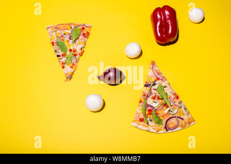 Mise à plat photo de deux tranches de pizza et quelques légumes isolé sur fond jaune Banque D'Images