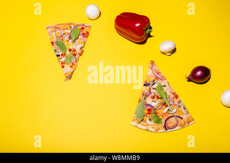 Mise à plat photo de deux tranches de pizza et quelques légumes isolé sur fond jaune Banque D'Images