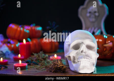 Crâne menaçant pour Halloween party assis sur une table en bois avec des citrouilles. Crâne humain hanté. Banque D'Images