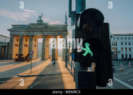 Feu vert de Berlin Ampelmann close-up avec la porte de Brandebourg à fond à l'aube Banque D'Images