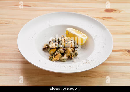 La plaque avec les moules marinées et tranche de citron sur la table en bois Banque D'Images