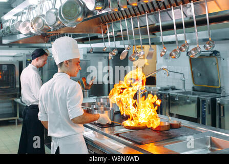 Cuisine moderne. Les cuisiniers préparent les repas sur la cuisinière dans la cuisine du restaurant ou hôtel. L'incendie dans la cuisine. Banque D'Images