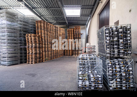 Grand entrepôt à l'usine, la cave, les bouteilles de vin dans des paniers métalliques prêt pour le transport, des piles de palettes en bois. Concept importateur de vin, Banque D'Images