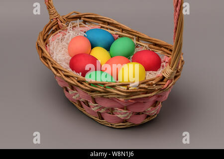 Neuf panier avec les oeufs de Pâques colorés sur un fond gris. Photographie horizontale Banque D'Images