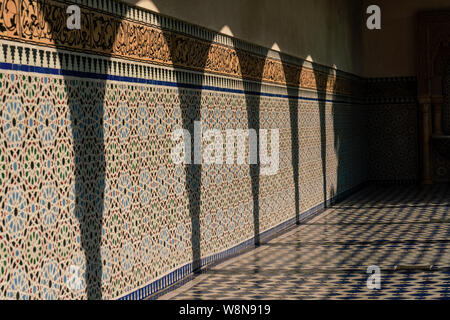 Ombres de piliers sur un mur carrelé de mosaïque en plein soleil Banque D'Images