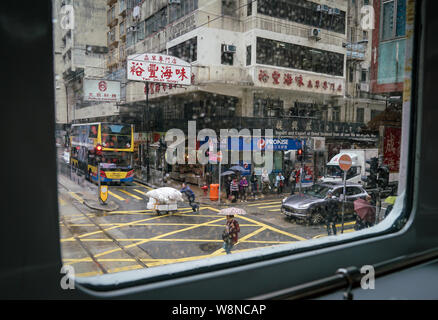 L'île de Hong Kong, Hong Kong-14th March 2019 : Les gens qui marchent dans la rue un jour de pluie.. Cliché pris depuis l'intérieur du tramway. Banque D'Images