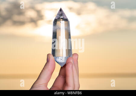 Vogel Style Double résilié Wand dans woman's hand au lever du soleil en face du lac. Banque D'Images