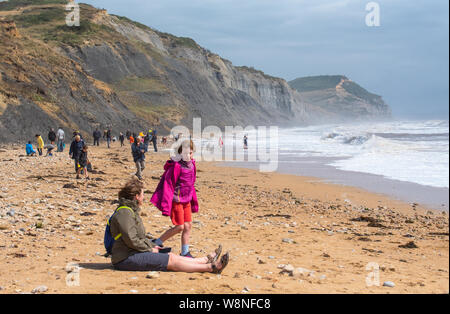 Charmouth, Dorset, UK. 10 août 2019. Météo France : Les vacanciers vous aventurer sur une journée venteuse au village balnéaire de Charmouth comme le temps exceptionnellement forts vents du sud-ouest continuent de battre la côte sud-ouest le samedi après-midi. Les conditions de tempête n'a pas dissuader les chasseurs de fossiles sur Charmouth plage. Credit : Celia McMahon/Alamy Live News. Banque D'Images