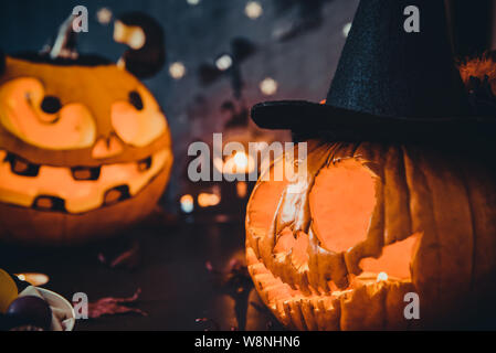 Close up deux citrouilles lumineux avec des visages mal effrayant, brûler des bougies et de silhouettes de papier de chauves-souris, château, fantômes sur fond noir en noir. Banque D'Images