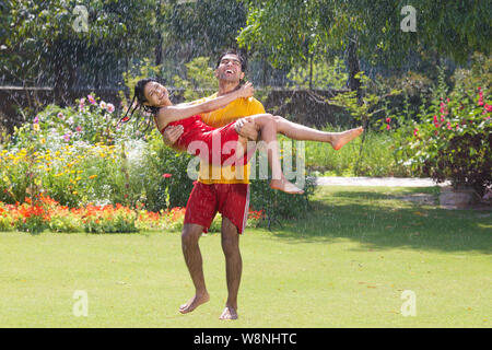 Jeune couple dans un jardin de pluie Banque D'Images