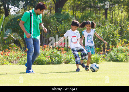 Famille jouant au football dans un jardin Banque D'Images