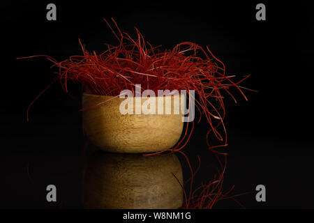 Lot de piment rouge vif threads dans bol en bois isolé sur verre noir Banque D'Images
