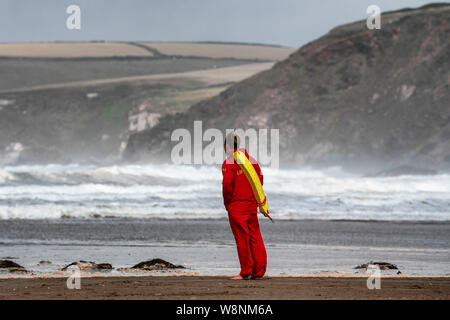 Un sauveteur RNLI en devoir sur la plage à Bigbury-on-Sea dans le sud du Devon en conditions orageuses au cours de l'été. Banque D'Images