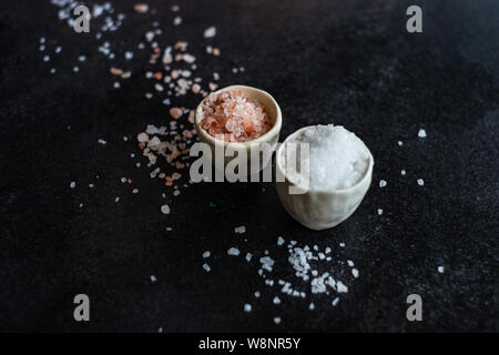 Concept de cuisson avec du sel de l'himalaya et rose variété sel de mer blanc dans le bol en céramique pierre sombre contexte with copy space Banque D'Images