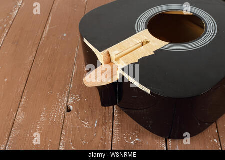 Service d'entretien et de réparation de guitare - Fragment de la carte son de guitare acoustique cassé fond de bois Banque D'Images