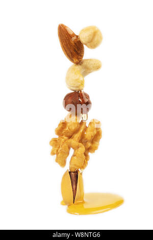 Divers Écrous sur fond blanc ; bannière. Assortiment - noisette, noix, pistaches, noix de cajou, amandes et miel dégoutter. Banque D'Images