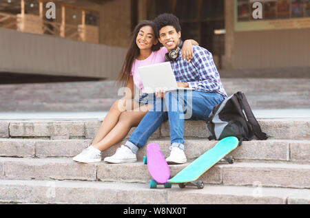 Couple d'adolescents noirs assis sur des escaliers avec portable Banque D'Images