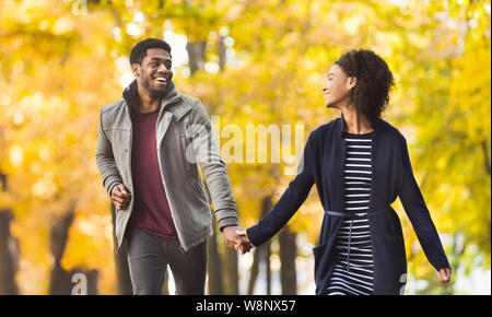 Heureux couple fonctionnant ensemble dans autumn park Banque D'Images