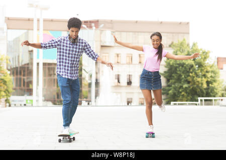 Les adolescents gais racing sur skateboards contre cityscape Banque D'Images