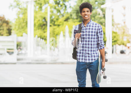 Beau mâle adolescent avec skateboard poser à huis clos Banque D'Images