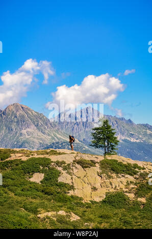 Photo verticale de l'homme seul errant dans les montagnes à une belle journée ensoleillée. Debout sur le bord d'un rocher. Backpacking traveler. La vie active concept. Banque D'Images