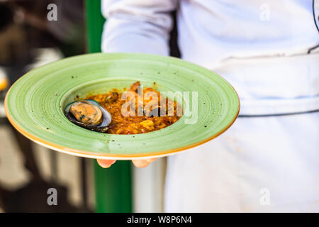 Assiette de risotto aux fruits de mer italiens dans la main du chef Banque D'Images