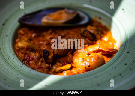 Risotto aux fruits de mer italien, servi avec un verre de vin blanc sec, les citrons et le sel sur fond de béton with copy space Banque D'Images