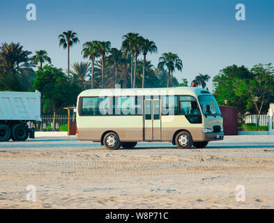 Autobus blanc dans le désert voyage. palmiers et ciel bleu clair Banque D'Images