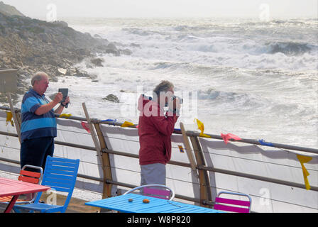 Plage de Chesil. 10 août 2019. Deux hommes braves le spray, de photographier les vagues gigantesques battues Chesil Beach, île de Portland. crédit : Stuart fretwell/Alamy Live News Banque D'Images