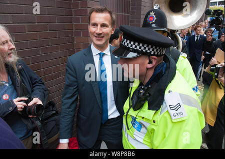 Manchester, UK. 7 octobre 2015. Le Secrétaire de la santé Jeremy Hunt a dû être escorté par la police en colère anti-austérité et anti-fracking protestataire Banque D'Images