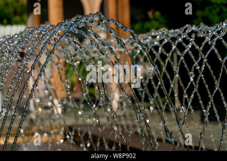 L'eau d'arrosage d'une fontaine avec des gouttes d'eau détaillée glinstering au soleil Banque D'Images