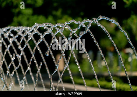 L'eau d'arrosage d'une fontaine avec des gouttes d'eau détaillée glinstering au soleil Banque D'Images