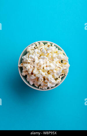 Dans un bol de pop-corn sur fond bleu, vue d'en haut Banque D'Images