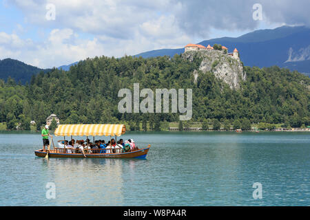 La Slovénie, Bled - Juillet 15, 2019 : turist traditionnel bateau. Beau lac de montagne en été avec un château sur la falaise et les Alpes en arrière-plan. Banque D'Images