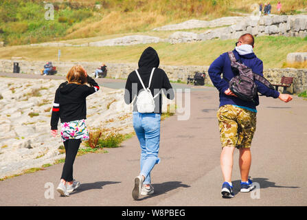 Plage de Chesil. 10 août 2019. Météo britannique. Une famille se dépêcher le long de la promenade du Portland Fin de tempête-fouetté Chesil Beach. crédit : Stuart fretwell/Alamy Live News Banque D'Images