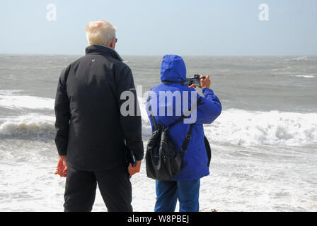 Plage de Chesil. 10 août 2019. Météo britannique. Un vieux couple de photographier les vagues gigantesques battues Chesil Beach, île de Portland. crédit : Stuart fretwell/Alamy Live News Banque D'Images