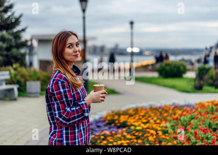 Café sur le rendez-vous. Belle jeune femme holding Coffee cup and smiling in the park Banque D'Images
