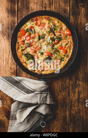 Frittata aux légumes avec le brocoli, le poivron rouge et les herbes dans la poêle en fonte. Vue de dessus Banque D'Images