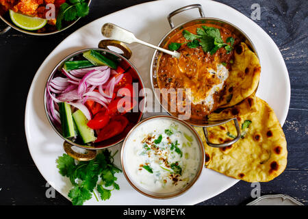 Repas curry indien noir avec les lentilles dal, salade, pain naan et raita Banque D'Images