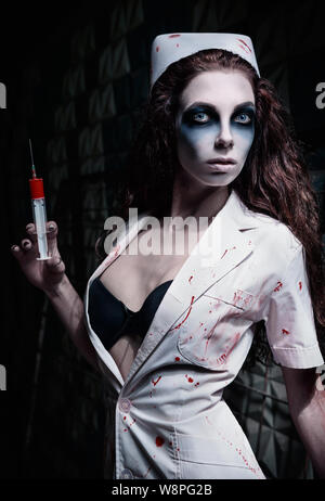Capture d'horreur : l'étrange infirmière médecin (MAD) dans bloody uniforme, avec la seringue dans la main. Femme Zombie (morts-vivants) Banque D'Images