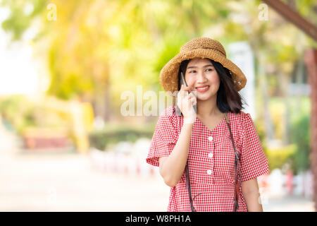 Les femmes asiatiques touristes utilisent téléphone intelligent et souriant à la gare de couleurs vives. Banque D'Images