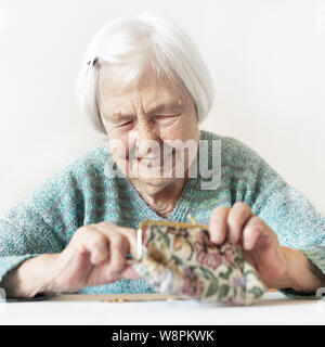 Personnes âgées gaies 96 ans woman sitting at table à la maison heureux avec elle dans son portefeuille d'épargne-retraite après le paiement des factures. Banque D'Images