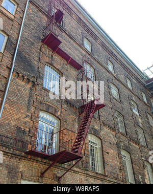 Mur de briques avec escalier en fer rouge et échelle Banque D'Images