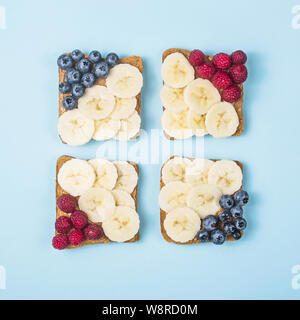 Petit-déjeuner sain composé de sandwichs avec du beurre d'arachide, banane et fruits rouges sur un fond bleu vif. haut Vue, télévision lay Banque D'Images