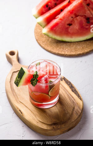 Un verre de jus de melon d'eau froide avec de la glace et garnir de menthe citron vert à côté de quelques morceaux de pastèque en tranches Banque D'Images
