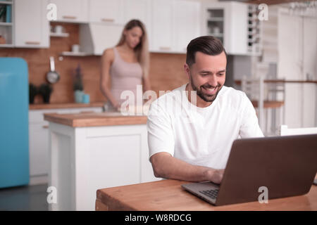 Jeune homme utilise en cuisine accueil ordinateur portable Banque D'Images