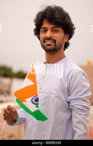 Portrait d'un jeune Indien man holding drapeau indien en robe traditionnelle indienne. Banque D'Images