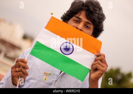 Portrait d'un jeune Indien man holding drapeau indien en robe traditionnelle indienne. Banque D'Images